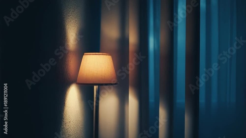 Warm glow from a standing floor lamp providing comfort and intimacy in a dimly lit room, with blurred blue curtains creating a calm, atmospheric and tranquil background