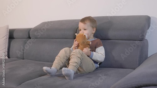 Little boy watching television holding a stuffed animal