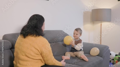 Grandmother and grandson playing with balloon on couch