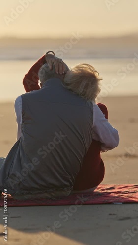 Elderly couple embracing on beach blanket at sunset