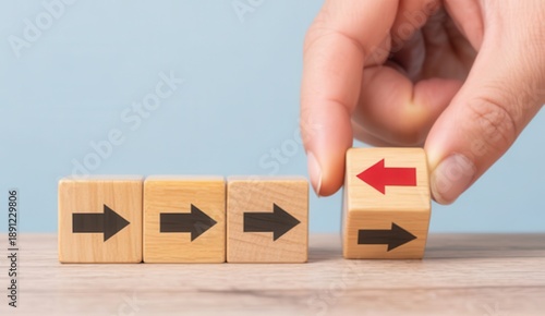 Hand changing direction of wooden block arrow from right to left, concept of change, decision making or going against the flow