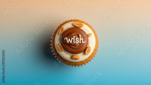 Overhead view of a single cupcake with white frosting, chocolate swirl, peanuts, and the word wish written on top, set against a blue and orange gradient background