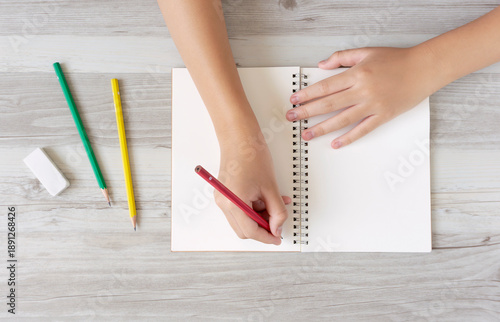 A child writing letters or illustrations in a notebook. ノートに文字またはイラストを書く子供