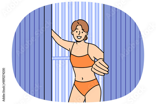 Woman comes out of vertical solarium, urging people to stop sunbathing, which causes skin cancer due to ultraviolet light. Girl visitor solarium stands in swimsuit, enjoying visit SPA treatments