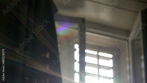 Out of focus window light and rainbow lens flare over soft background with subtle floating dust in ambient interior space and reflective atmosphere