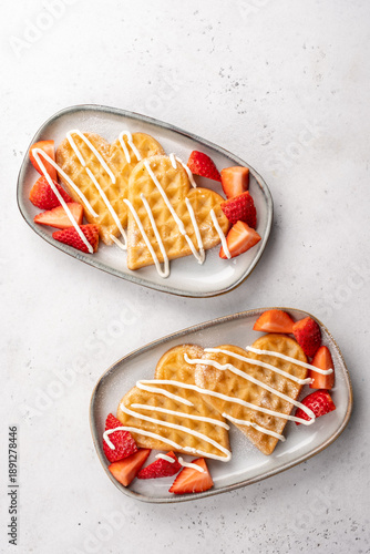 Heart-shaped waffles with strawberries served on plates during breakfast or brunch time