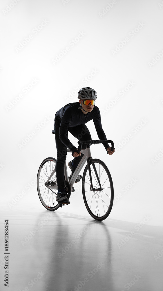Fototapeta premium Cyclist riding road bike in side view isolated on white background. Concept of movement analysis, cycling technique, endurance sport, and professional athlete lifestyle.