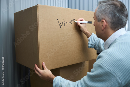 Foto Middle aged Caucasian man labeling large cardboard box with marker, writing word