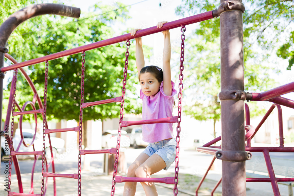 Obraz premium Child playing on monkey bars, exercising and developing strength at a sunny playground during summer
