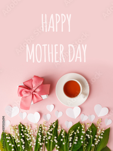 Bouquet of flowers, cup of tea, gift box, paper hearts on a pink background. Concept of romance holiday, woman day, text happy mother day, copy space, greeting card