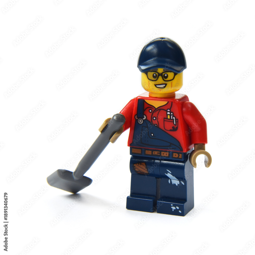 Naklejka premium Lego minifigure of a worker with a shovel isolated on white background. Editorial illustrative image of popular plastic toy.