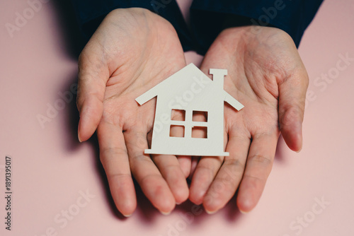 Buying a new house concept. Hands hold small house model, symbolizing home ownership and real estate. This conveys warmth and security associated with having home