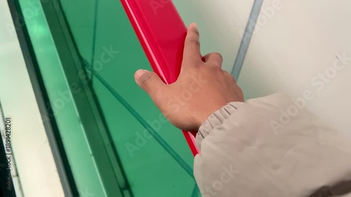 Close-up of hand playing lightly on red escalator handrail while wearing thick winter jacket during winter commute