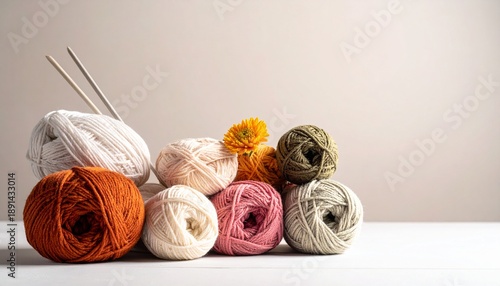Colorful yarn balls with knitting needles and a flower on a wooden table in bright light