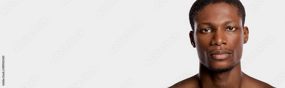 Fototapeta premium Handsome young man with a confident expression and striking features in a clean backdrop