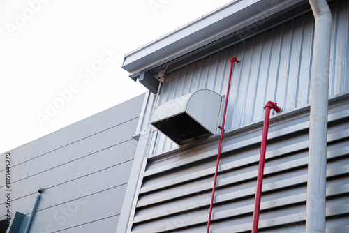 Factory Industry Exterior Background, Rainwater Drainage Pipelines with LED Solar Wall Lamps on Metal wall against Blue Sky, Warehouse Building with Ventilation Louver and Rain Gutter