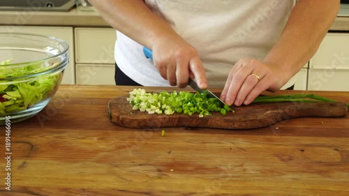 Woman cutting fresh green onion feathers for salad