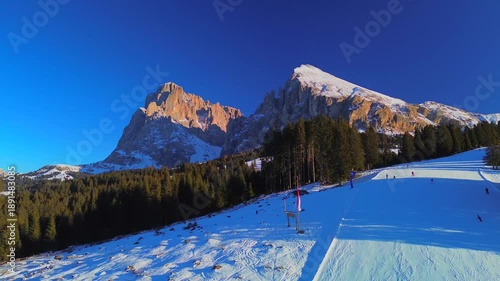 Aerial view. People skiing. Winter holidays. Snow-covered coniferous trees and roads on the tops of the Alpine mountains. Skier Winter. Wide angle drone view. Sun. Alpe di Siusi Italy 20.01.2026