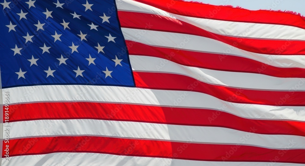 Obraz premium American flag waving proudly in the wind against blue sky