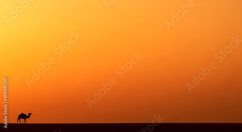 A solitary camel walks across a vast desert landscape under a vibrant orange and yellow sunset sky.