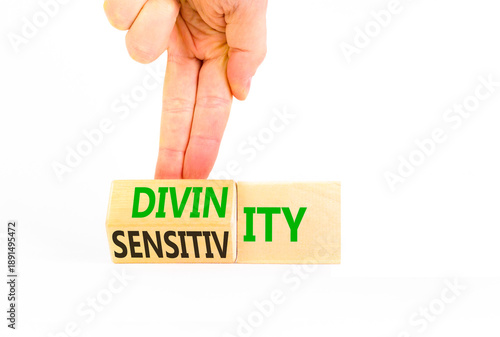 Sensitivity or divinity symbol. Concept words Sensitivity or Divinity on wooden cubes. Beautiful white background. Psychologist hand. Psychology sensitivity or divinity concept. Copy space.