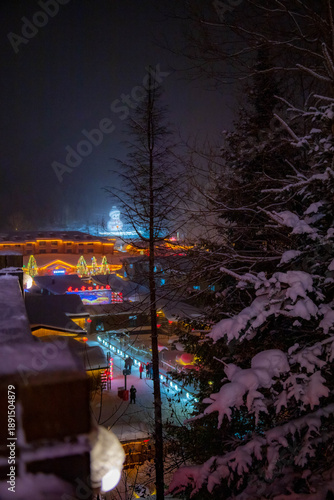 Snow clings to the branches, creating a magical contrast against the dark evening sky.
