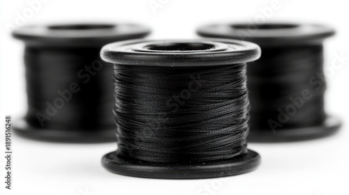Three spools of black thread are arranged in a row.
