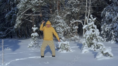 Man lifting kettlebell overhead in snowy winter forest, Outdoor strength exercise demonstrating endurance, balance and cold weather training