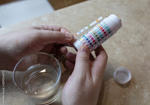 Wallpaper Mural A man in the kitchen tests tap water quality with a test strip. Home testing for drinking water safety, pH, chlorine, and chemical contaminants. Torontodigital.ca