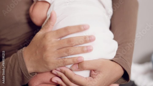 Wallpaper Mural A woman is holding a baby in her arms. The baby is wearing a white blanket. The woman is sitting on a chair Torontodigital.ca