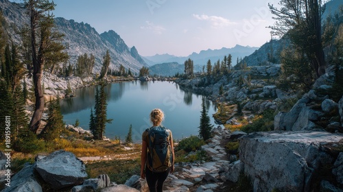 Quiet moment on a hiking trail: woman with backpack admiring an alpine lake and valley panorama