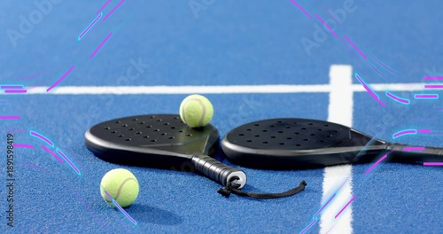 Showing black padel paddles resting on blue court near white lines with three balls and strap