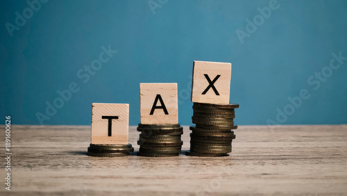 Ascending Coin Stacks with TAX Blocks on Blue Background Representing Tax Burden