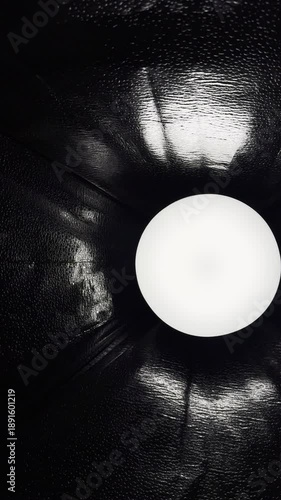 glowing white orb illuminating textured black reflective surface in dramatic abstract lighting composition