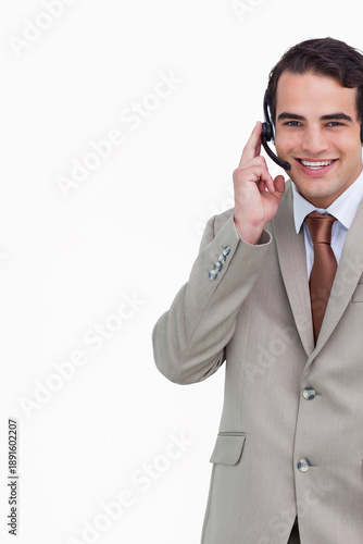 Male customer service rep holding headset and smiling in studio wearing beige suit, copy space