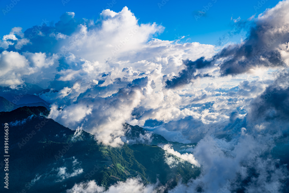 Fototapeta premium Aerial view of Hehuanshan, Renai, Nantou, Taiwan. Early autumn sun lights a winding mountain road above a sea of clouds and green slopes.
