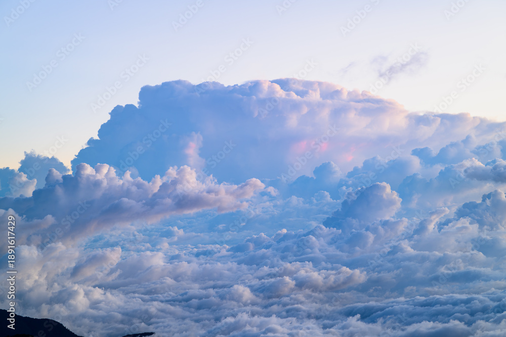 Fototapeta premium Breathtaking aerial view of rolling clouds over Hehuan Mountain, Taiwan during a clear autumn day. Lush green mountain ranges under a vibrant blue sky.
