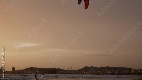 Kitesurfer in motion at sunset, extreme sport on the tropical beach.