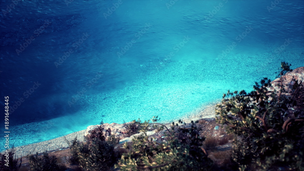 Fototapeta premium Gentle waves lap at a tranquil shoreline where vibrant blue waters meet a pebbled beach. Lush trees frame the scene, creating a peaceful retreat in natures embrace.