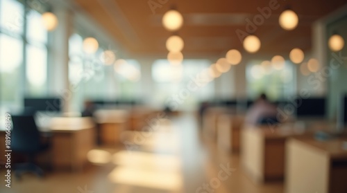 Warmly lit blurred office interior with hanging round pendant lamps and wooden desks in open workspace environment reflecting cozy professional workplace design and evening business mood