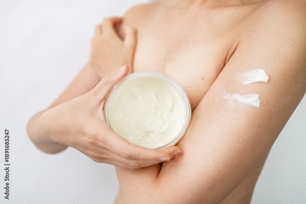 Fototapeta premium Asian woman applying body cream on arm, beauty skin care concept.