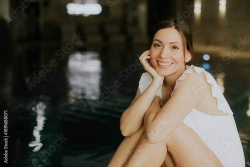 Woman sits by pool and smil...