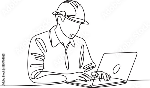 Engineer working on laptop at desk in office environment viewed from side