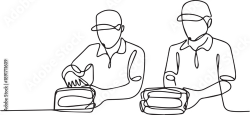 Two men in caps working together on machinery beside a table, viewed from the front