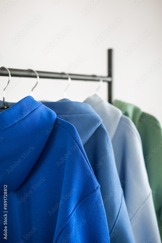 Obraz premium Various hoodies hanging on a rack in a simple indoor setting during daylight hours