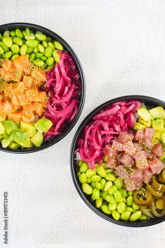 Two healthy poke bowls with salmon and tuna on white table
