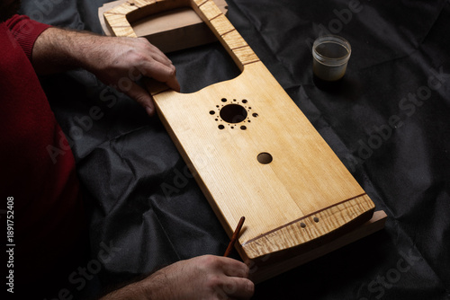 The master holds the finished body of the talharpa in his hands