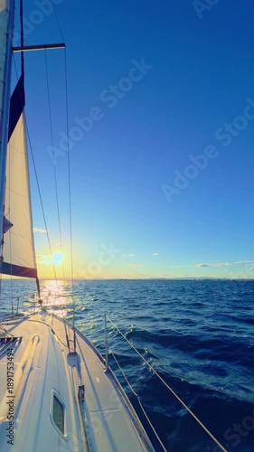 Valencia sailboat at sunset cruising on Mediterranean sea with golden light
