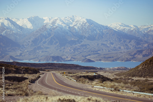 Scenic mountain road with snowy peaks and reservoir