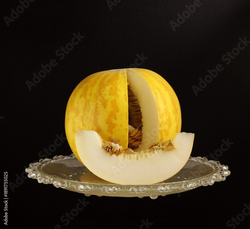 Image of a cut melon on a plate on a dark background.
